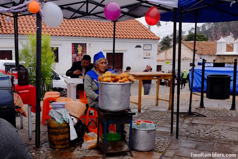 Lady with a big pot of humitas in front of her at a food stand