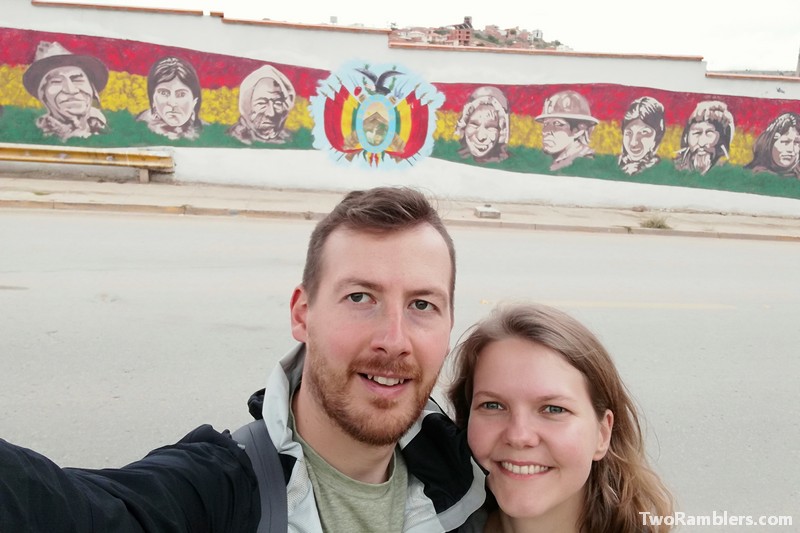 Two people in front of mural in colours of Bolivian flag