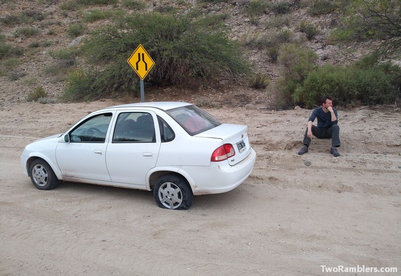 Car with flat tire on sand road